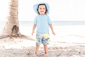 Little boy on the beach wearing a beach hat and a blue tshirt