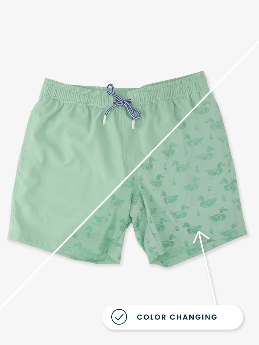 Line drawing of Sage Mallards Color Changing Men's Performance Hybrid Swim Trunks. A dotted circle indicates the approximate location for personalization.