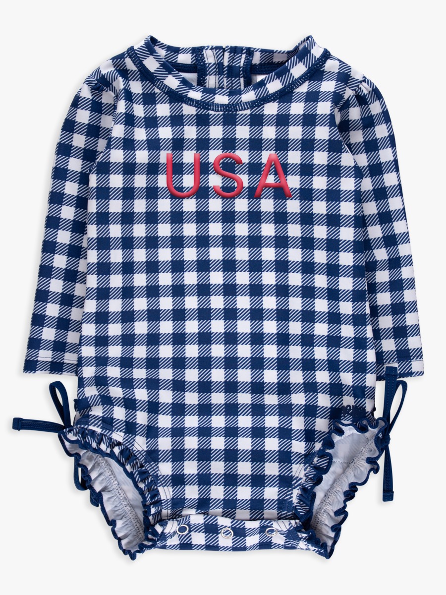 Line drawing of Red USA Embroidered Navy & White Gingham Long Sleeve One Piece Rash Guard Swimsuit, with Signature Rear Ruffles. A dotted circle indicates the approximate location for personalization.