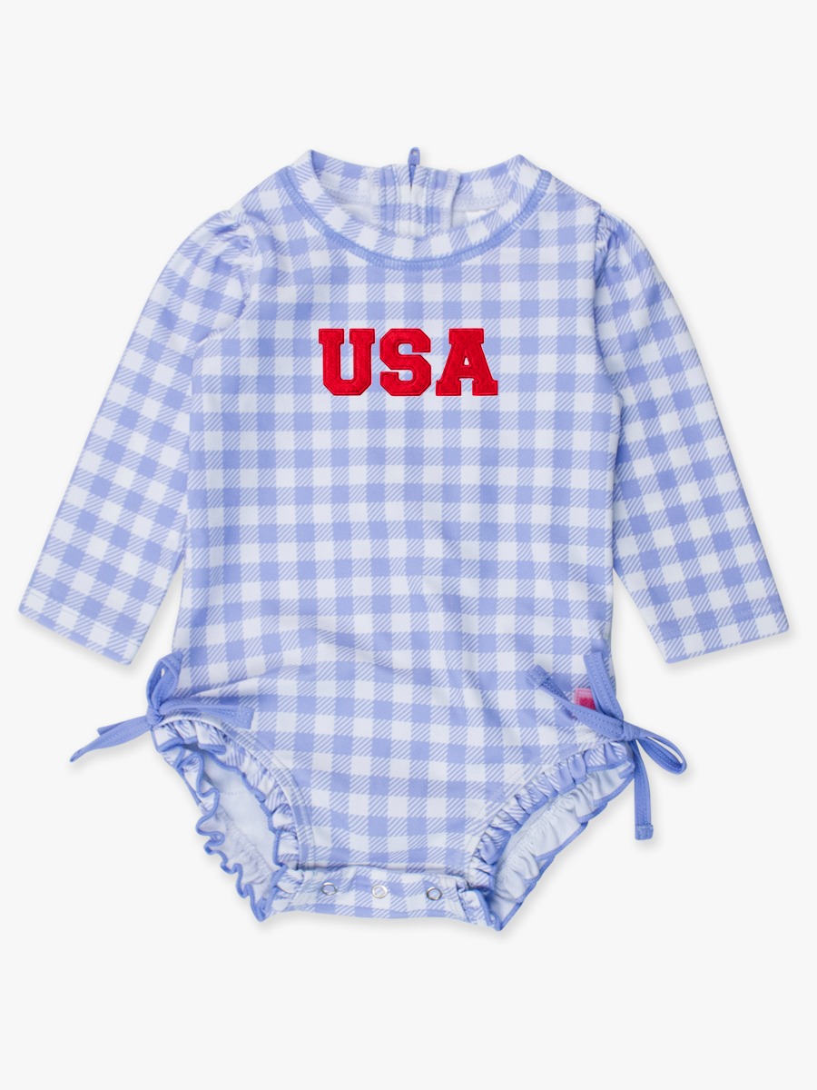 Line drawing of Red USA Embroidered Periwinkle Blue Gingham Long Sleeve One Piece Rash Guard Swimsuit, with Signature Rear Ruffles. A dotted circle indicates the approximate location for personalization.