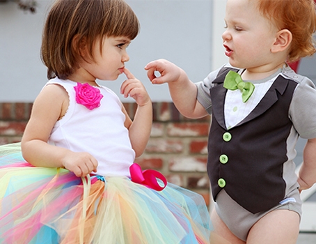 A girl and a boy wearing a tutu and a baby boy tuxedo garment