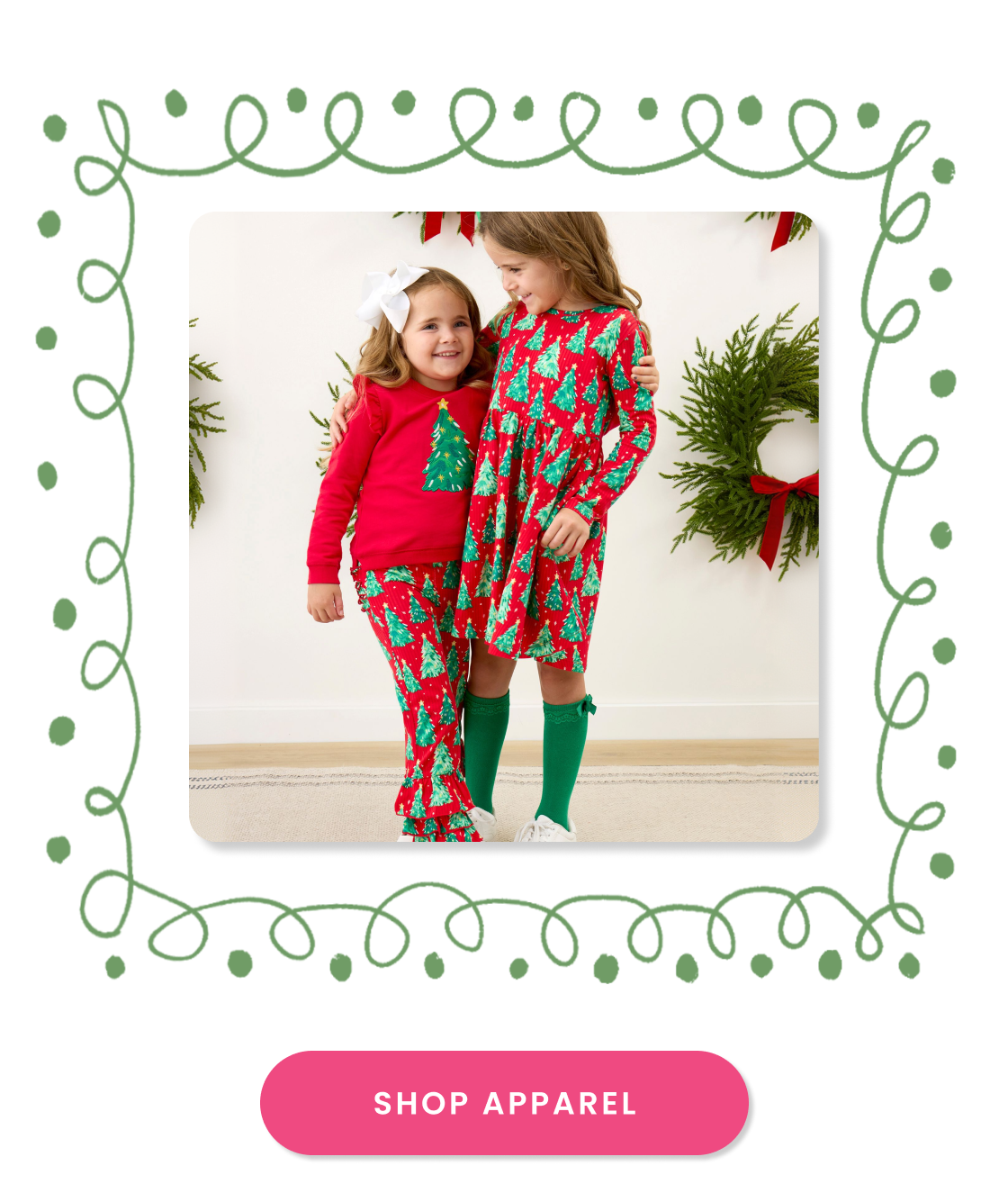 Promotional image showing two children wearing coordinating Christmas tree print apparel in a festive setting with wreath décor. Call-to-action button reads ‘Shop Apparel.