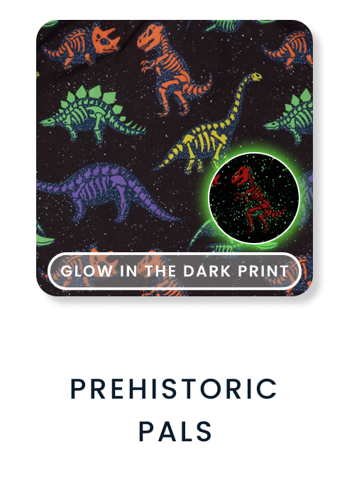 Shop By Print tile featuring a black pattern with colorful glow‑in‑the‑dark dinosaur skeletons. Text reads ‘Glow in the Dark Print’ and ‘Prehistoric Pals